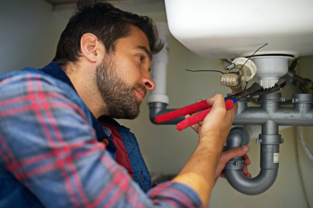 Plumber tightening pipe with wrench